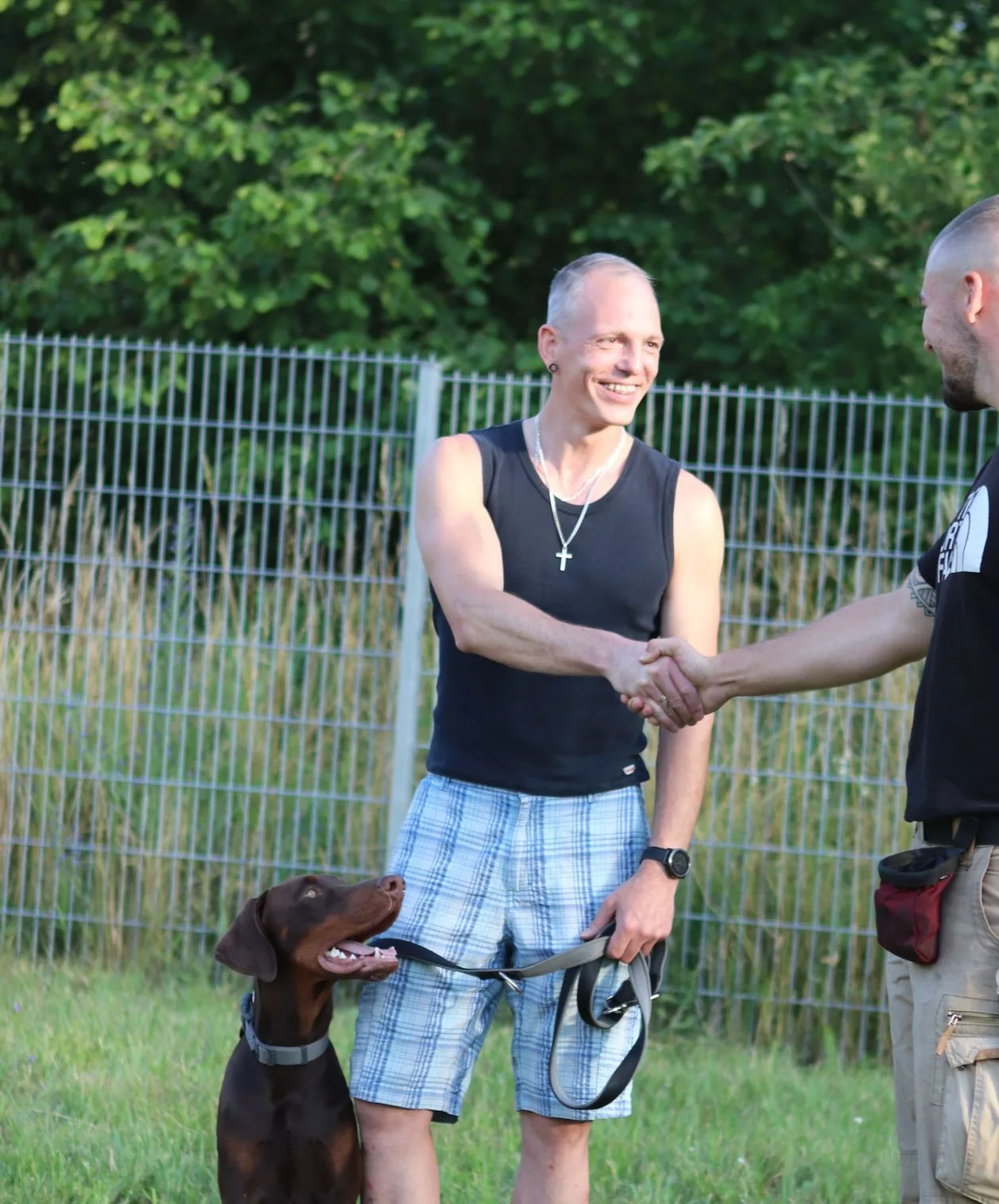 Leon Weisbecker reicht einem zufriedenen Hundehalter die Hand, der Hund sitzt daneben