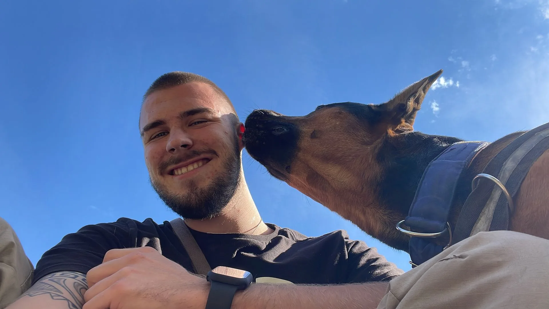Leon Weisbecker lächelt in die Kamera, während ihm sein Hund über die Wange schleckt